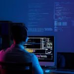 Developer working on code late at night, view from the back